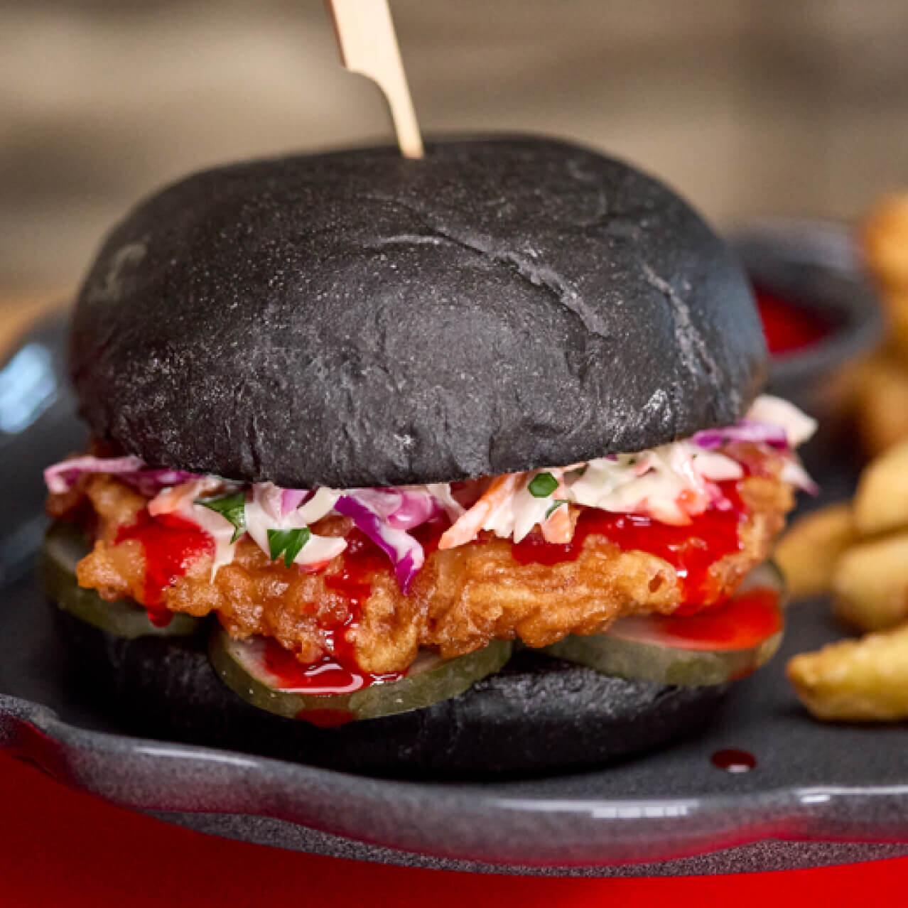 “Blood” Orange Chicken Sandwich with a black bun is available at Das Stakehaus in Dark Universe.