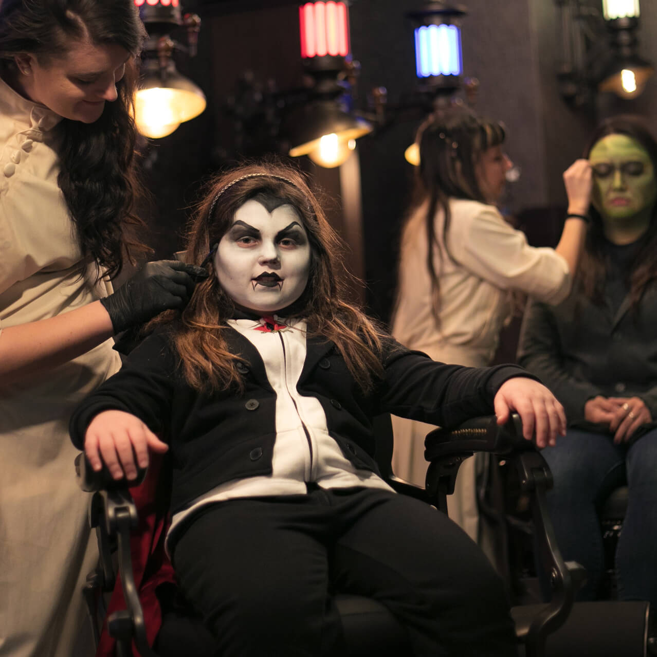 A young customer is transformed into a vampire with face makeup by a skilled artist at Darkmoor Monster Makeup Experience.