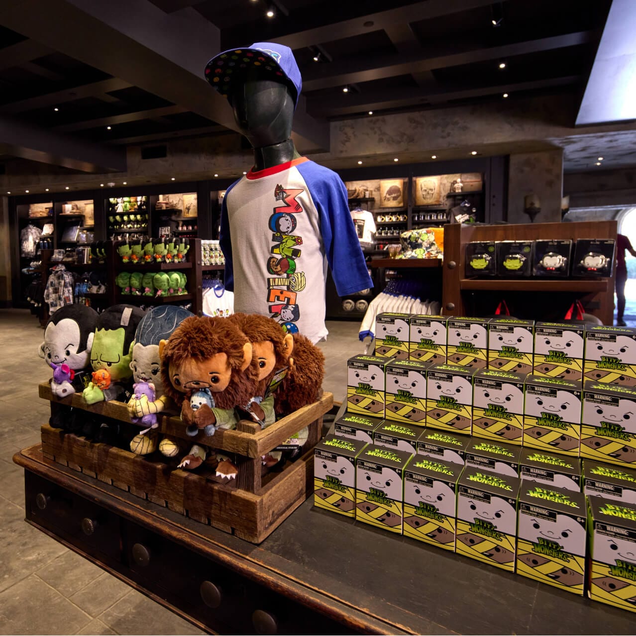 A merchandise display in Manor Storehouse, with apparel, plush monsters and boxed Bitty Monsters.