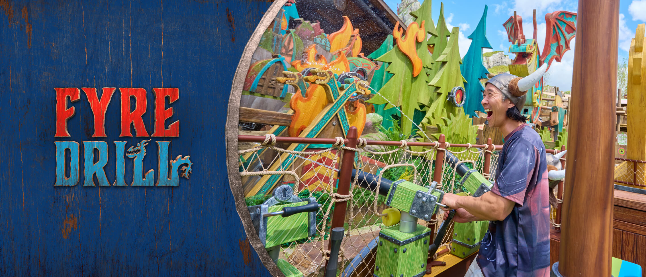 Fyre Drill logo and a guest wearing a Viking helmet laughs as he aims a water cannon at a target on Fyre Drill at How to Train Your Dragon - Isle of Berk.
