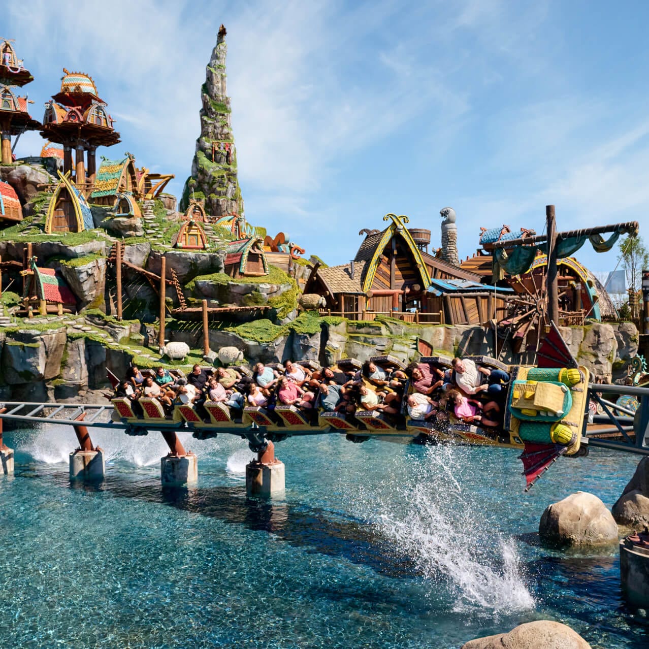 Riders enjoy Hiccup’s Wing Glider rollercoaster as it swoops just above the water with the Isle of Berk in the background.