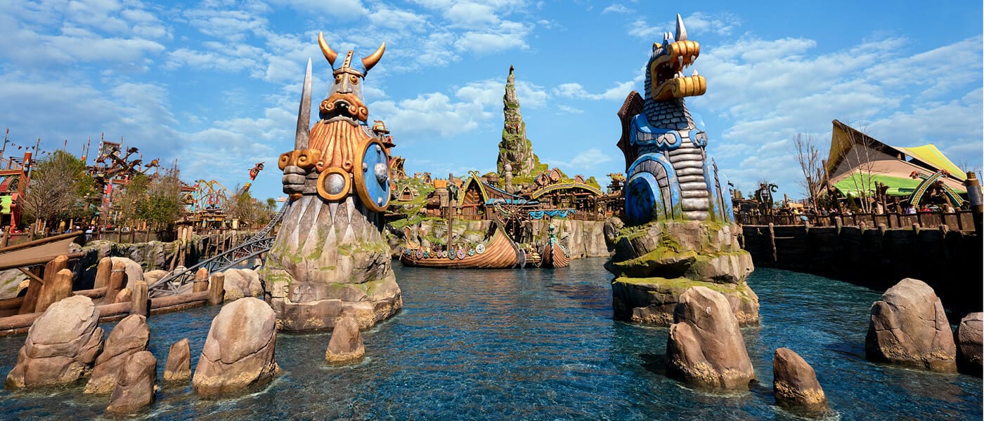 How to Train Your Dragon - Isle of Berk with Viking and dragon sentry statues, dragon houses, and Mead Hall rising in the distance.