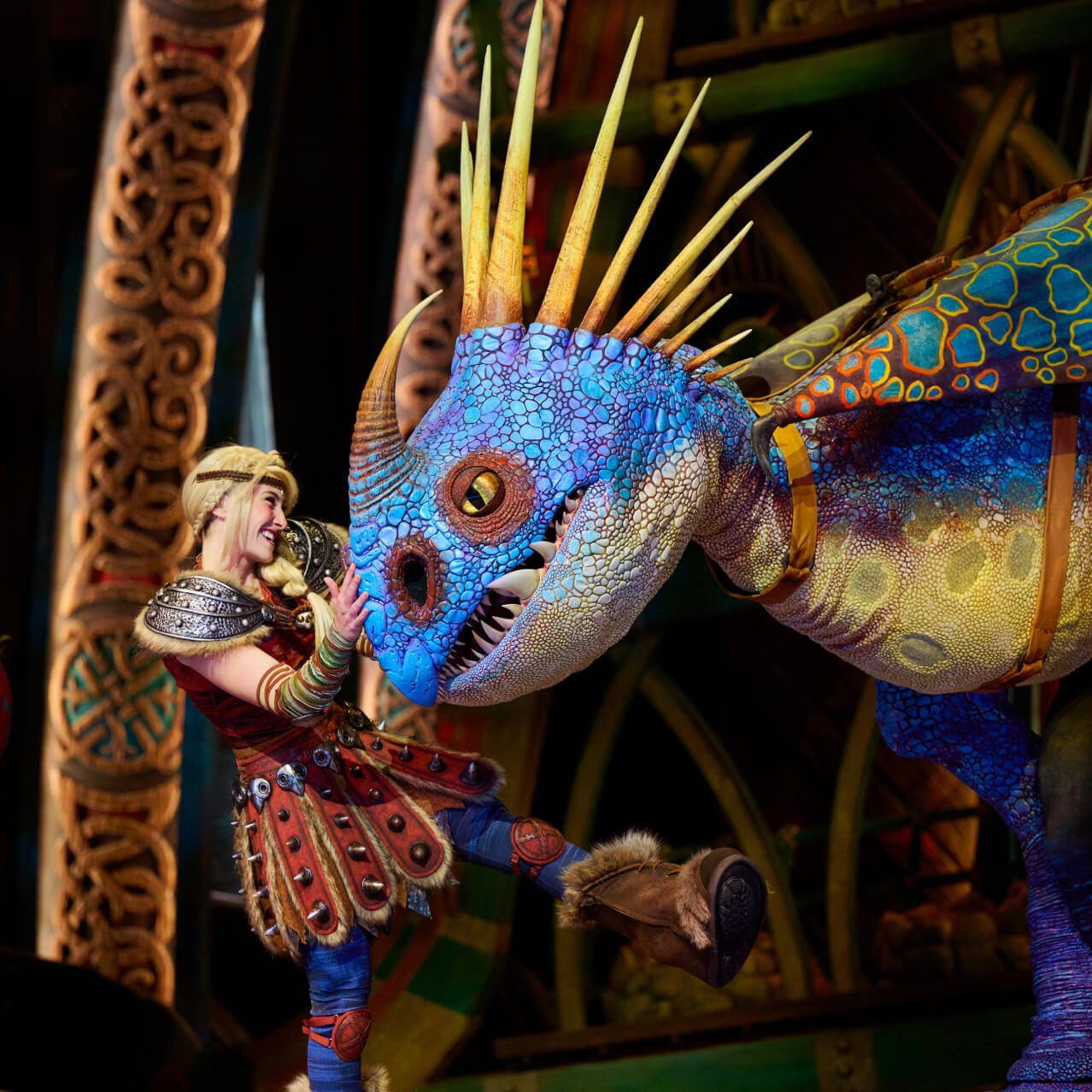 Astrid smiles and she pats Stormfly on the snout during The Untrainable Dragon live show at How to Train Your Dragon in – Isle of Berk in Universal Epic Universe.