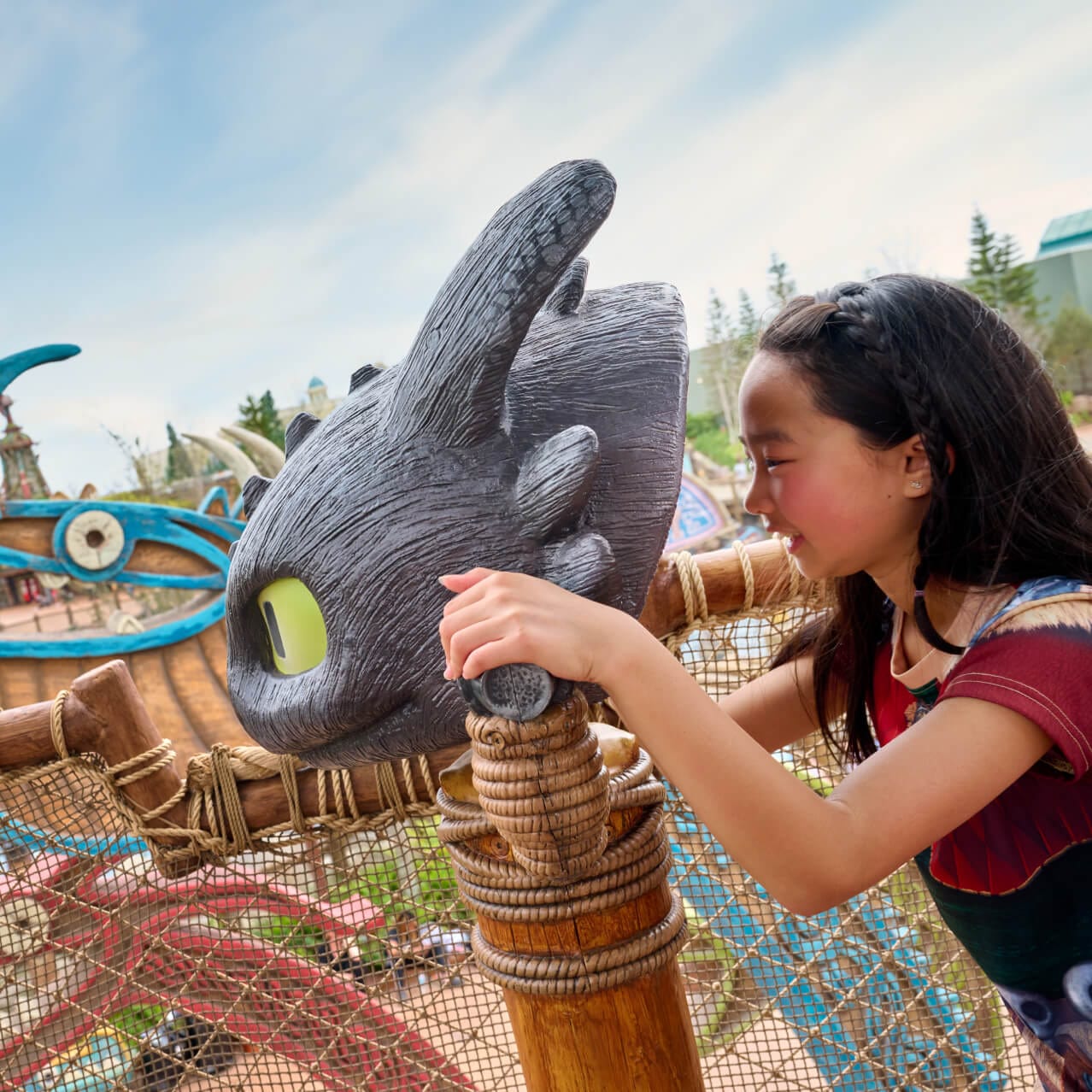 A young girl looks through a Toothless-shaped viewfinder at the Viking Training Camp in How to Train Your Dragon - Isle of Berk.