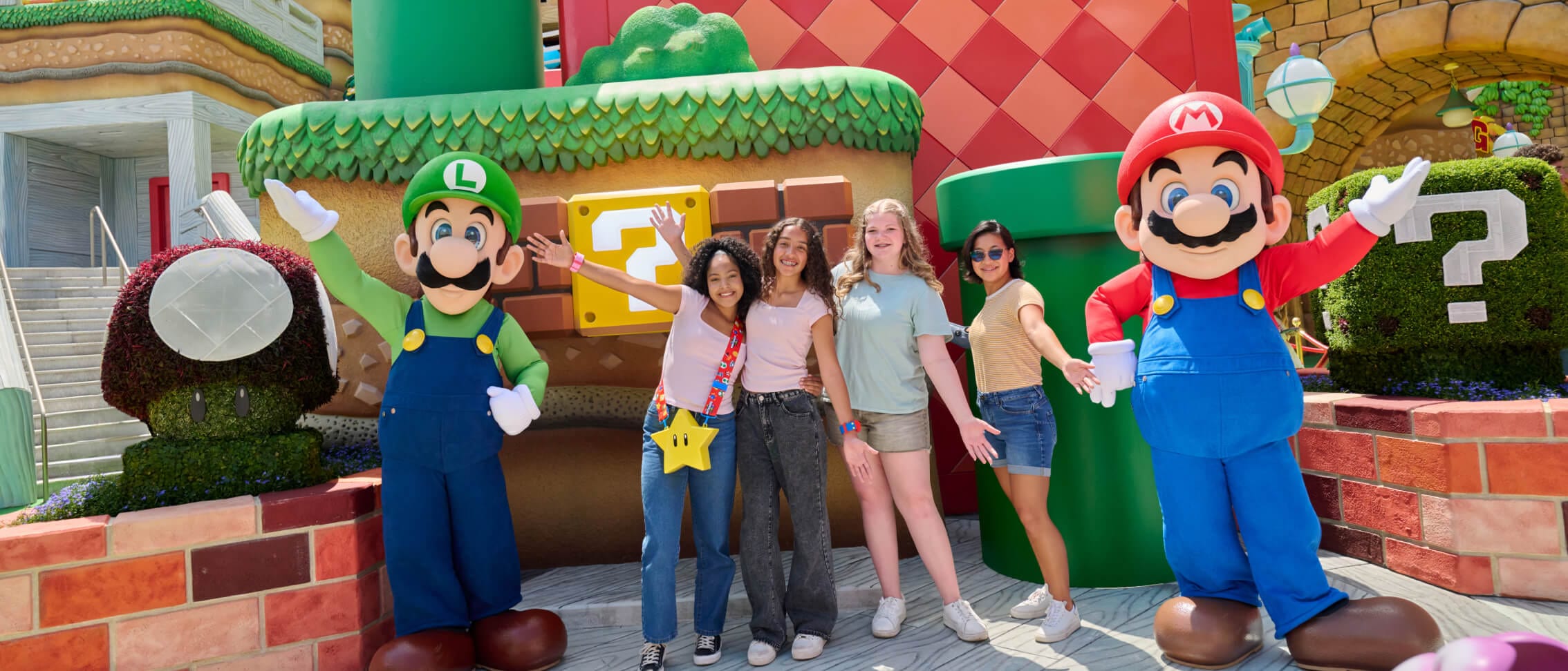 A group of friends pose with Mario and Luigi in SUPER NINTENDO WORLD™.