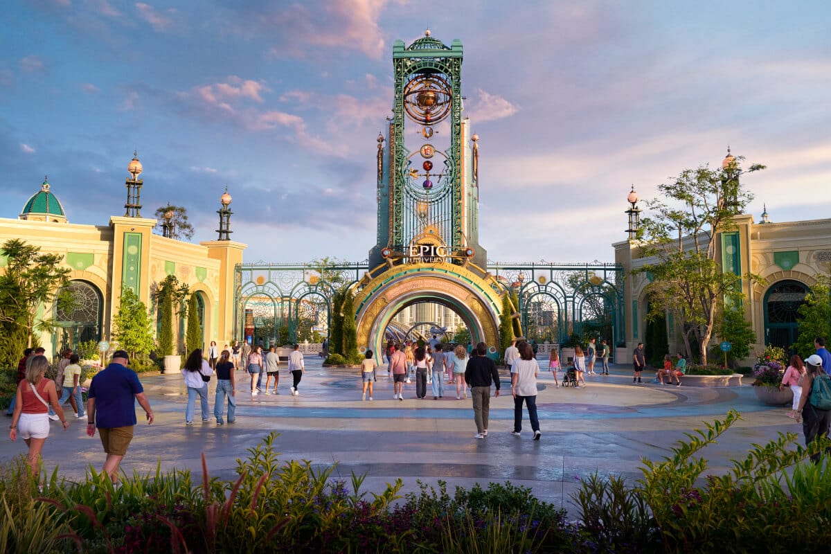 Guests walk toward the Celestial Park portal at the main entrance of Universal Epic Universe, with the Chronos rising overhead.