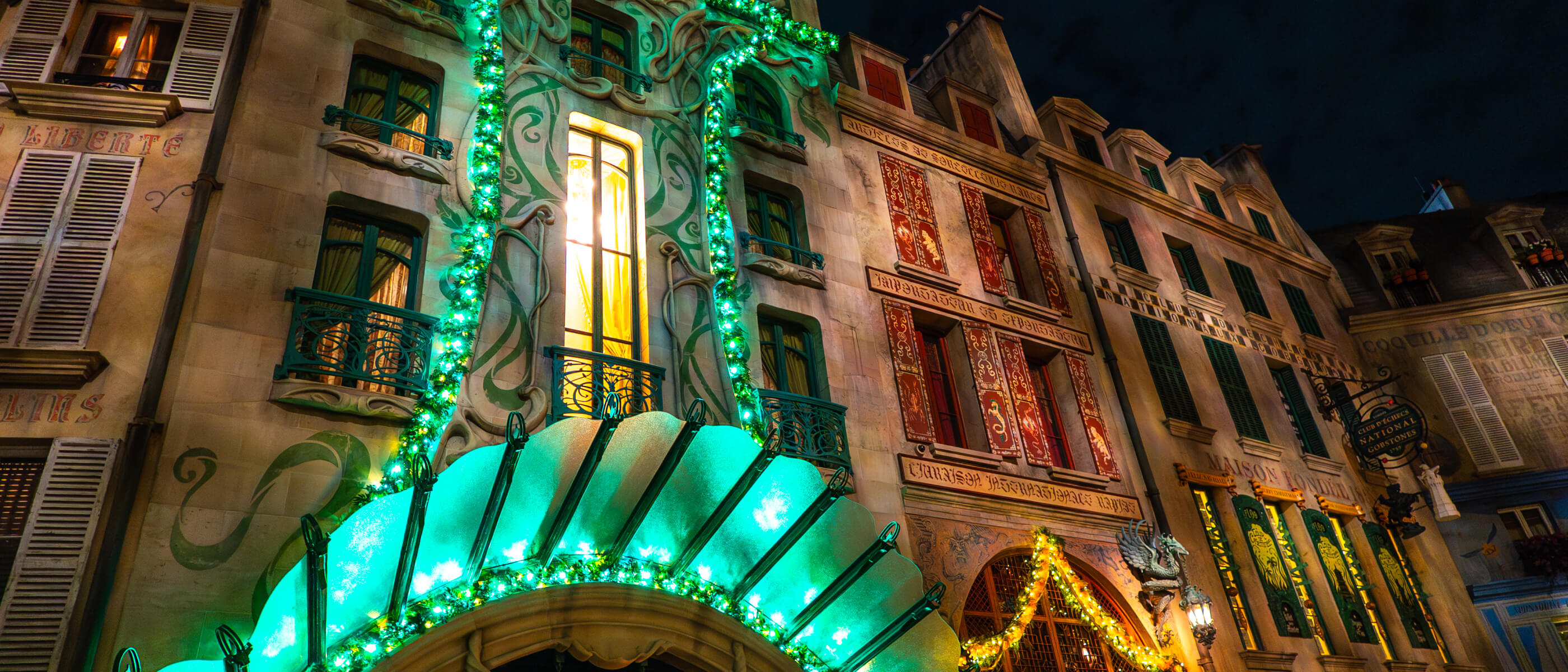 A decorated building facade glows with green lights and gold Christmas decor.