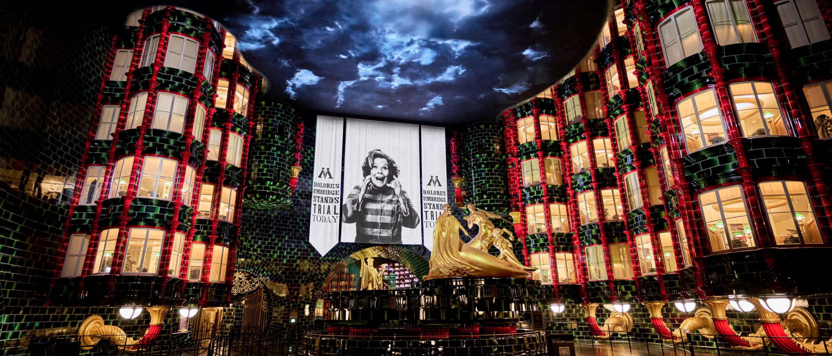 The interior atrium of the Ministry of Magic™ with golden statues, lit offices, a cloudy sky and a Dolores Umbridge banner.