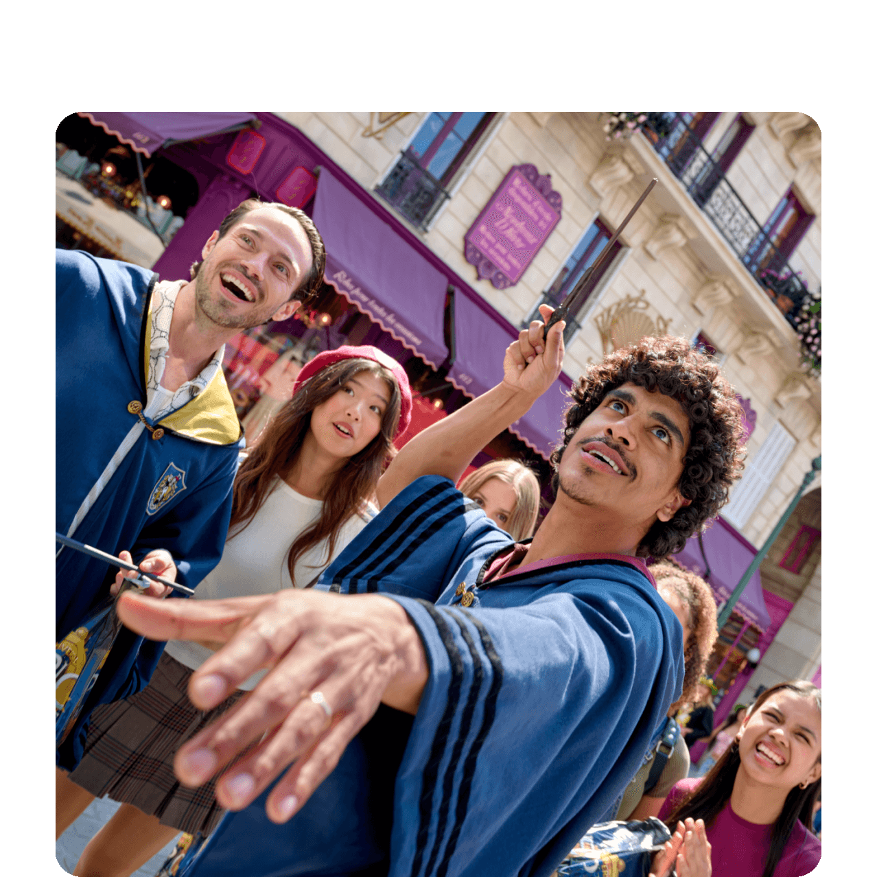 Friends wearing wizarding robes wave their wands in the air to cast spells in wizarding Paris