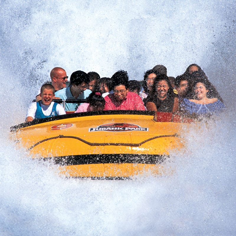 A giant splash erupts over riders on the Jurassic Park River Adventure water ride.