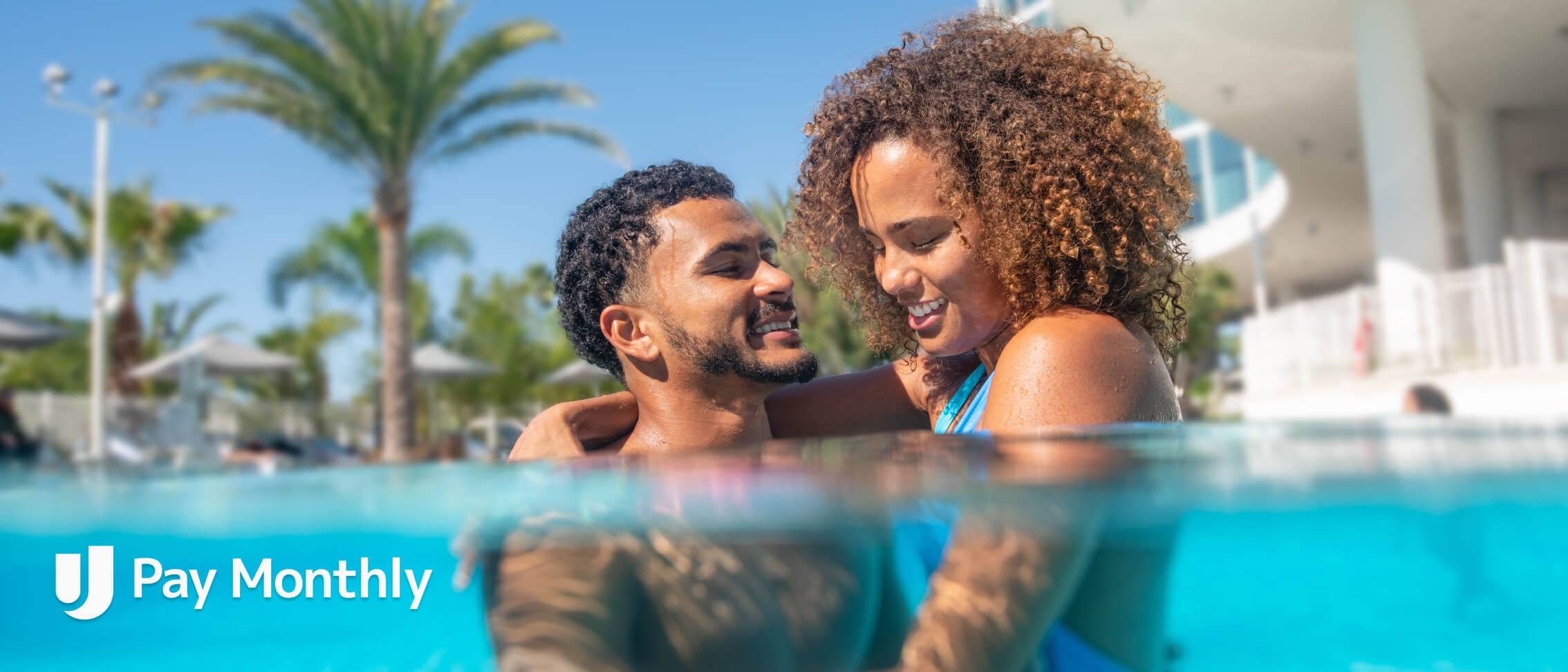 Couple splashing around and laughing while in the Aventura resort pool.