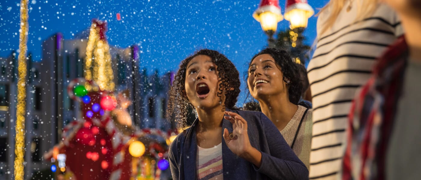 Snow falls toward a girl watching the Universal Studios Florida holiday parade.
