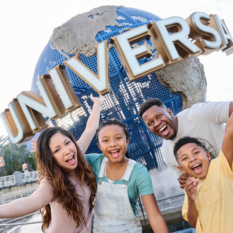 A family of four with two young kids posing front of with the Universal Globe.