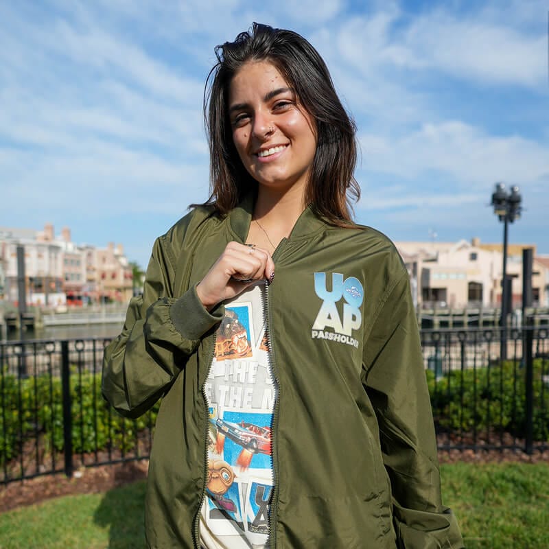 A woman wearing a dark green jacket with the UOAP Passholder logo on the upper left side.
