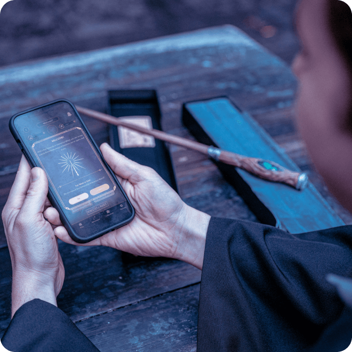 A wizard’s hands holding a phone next to a wand to pair the two with Universal Play.