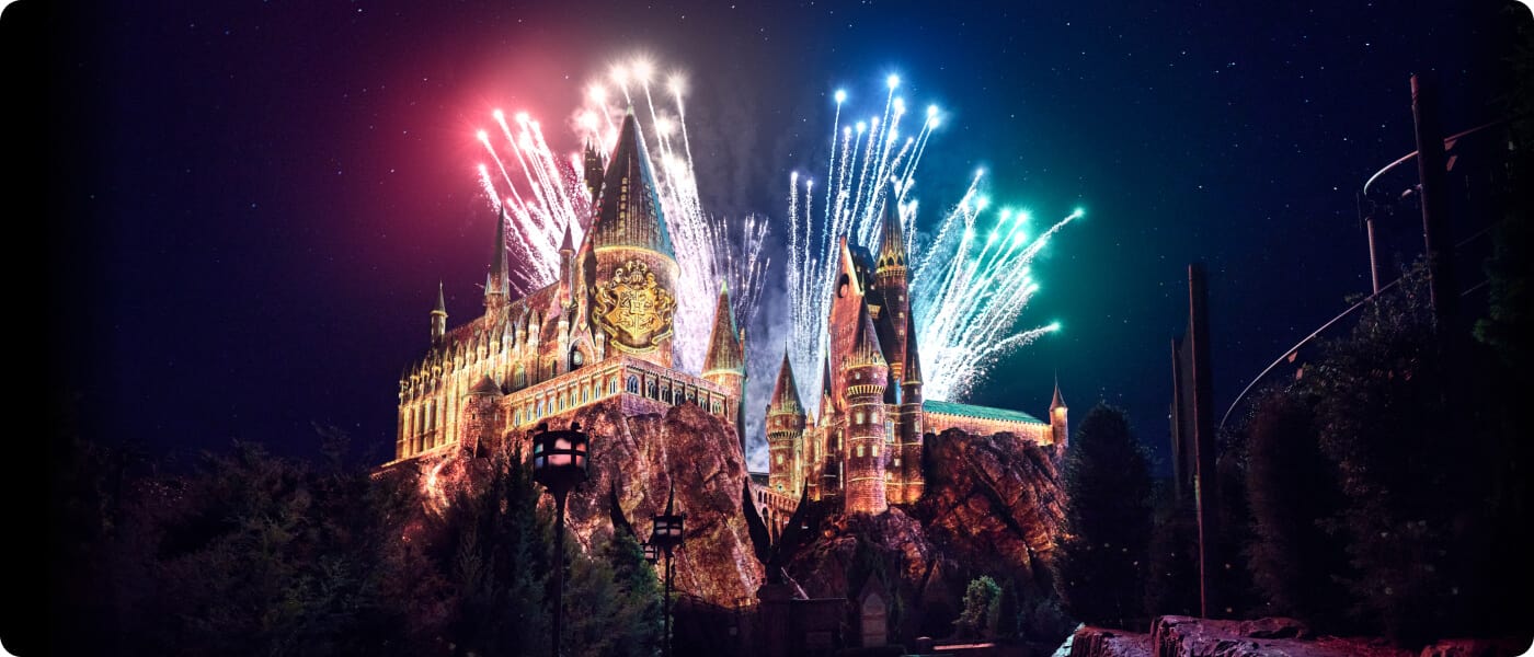 Colorful fireworks lighting up the night sky behind Hogwarts™ at The Wizarding World of Harry Potter™.