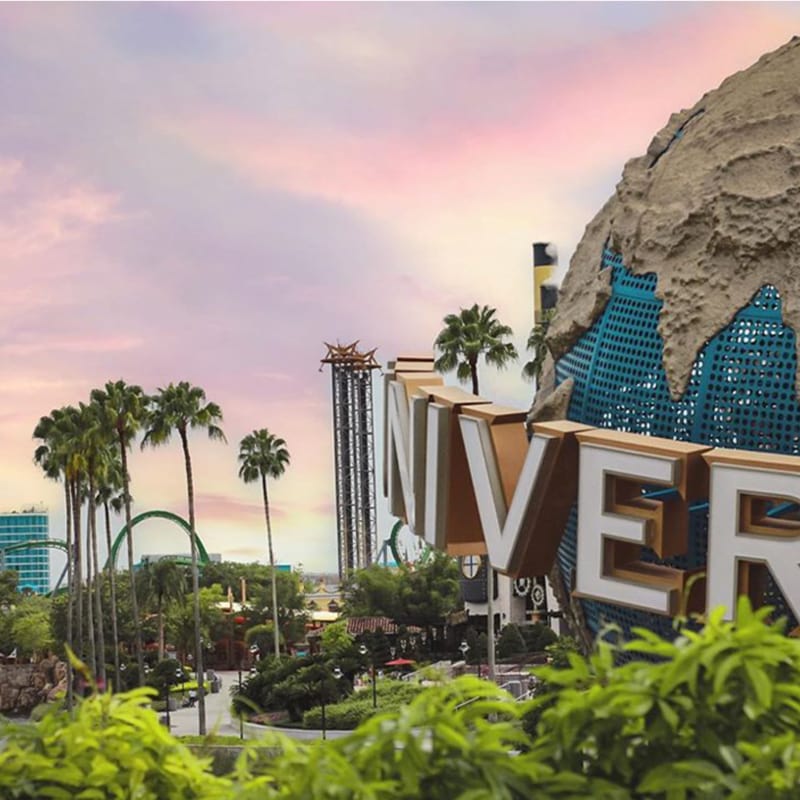 A close up view of the Universal globe at sunset with palm trees in the background.