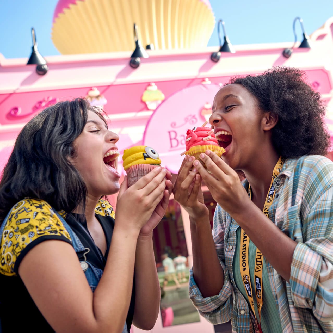 Two friends playfully eating cupcakes outside of Bake My Day in Universal Studios Florida.