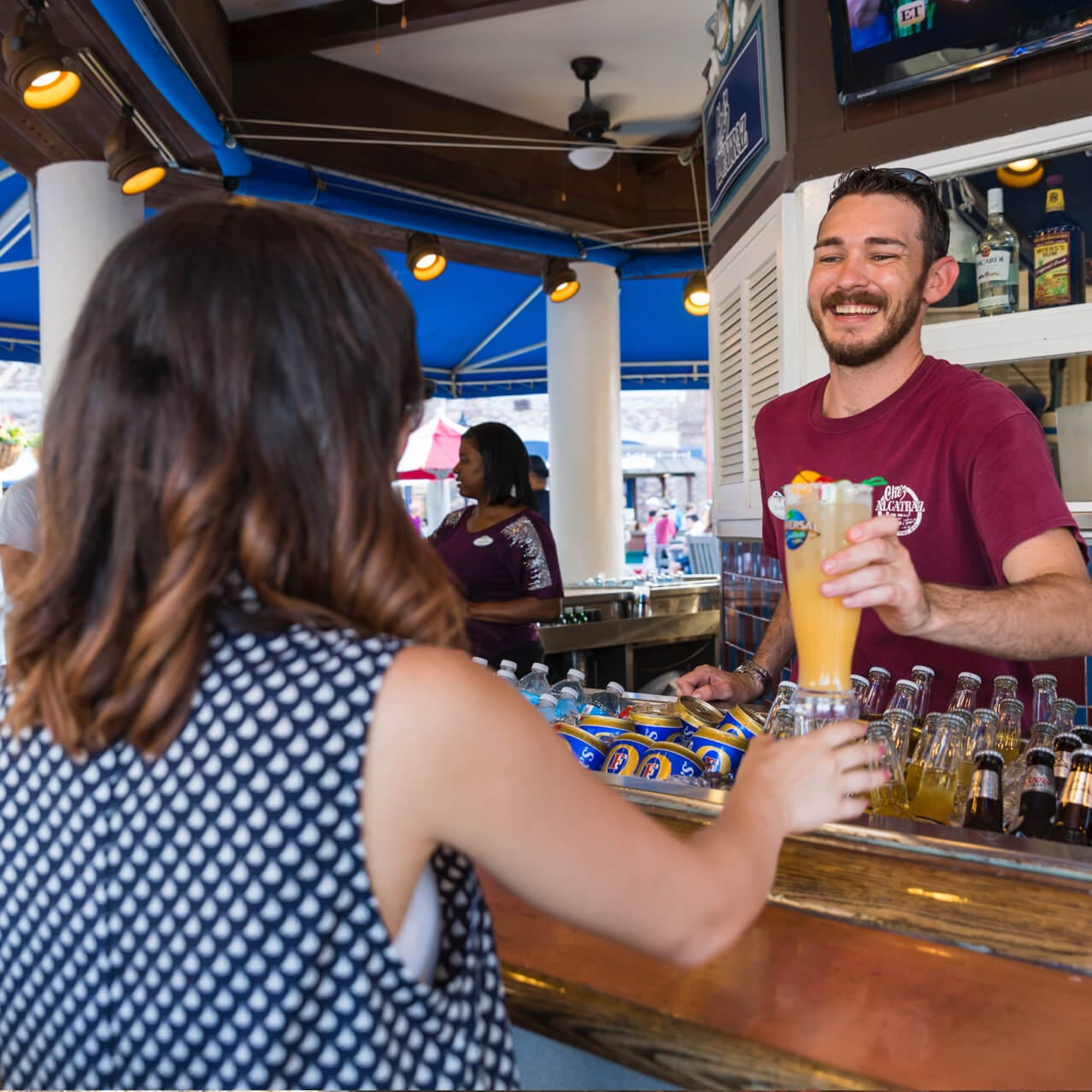 A bartender at Chez Alcatraz hands a guest a cocktail on the Fisherman’s Wharf in Universal Studios Orlando.
