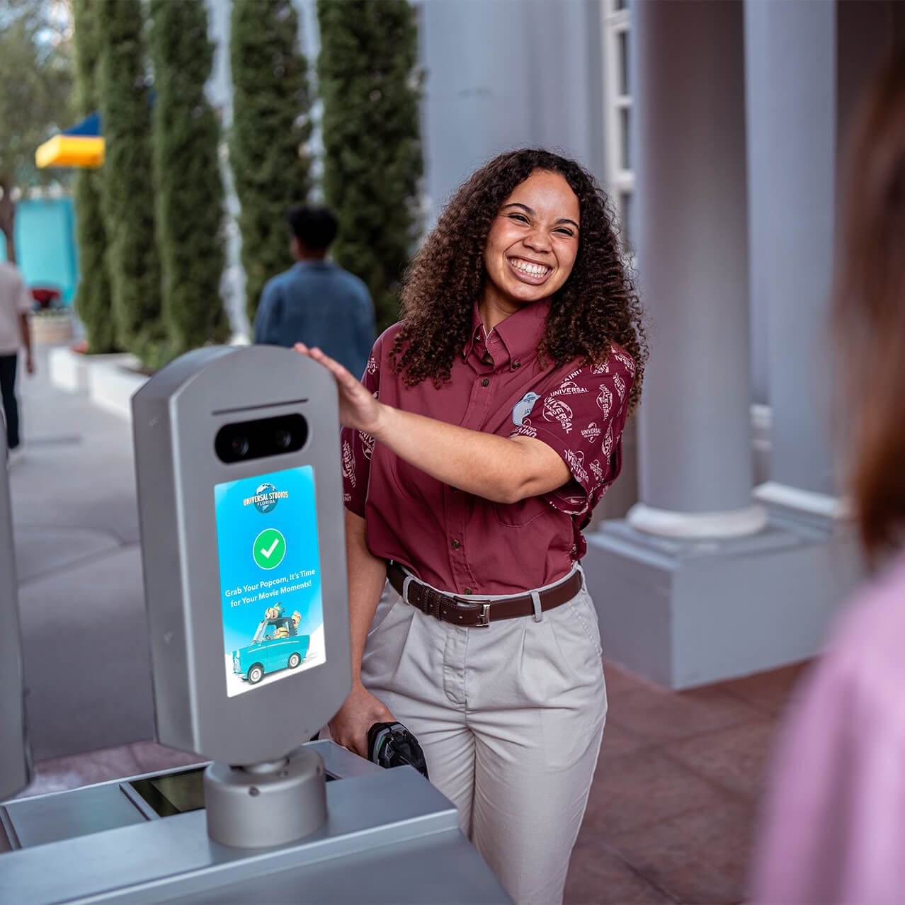 A Team Member smiling while directing guests to a Photo Validation screen for entry to Universal Studios Florida.