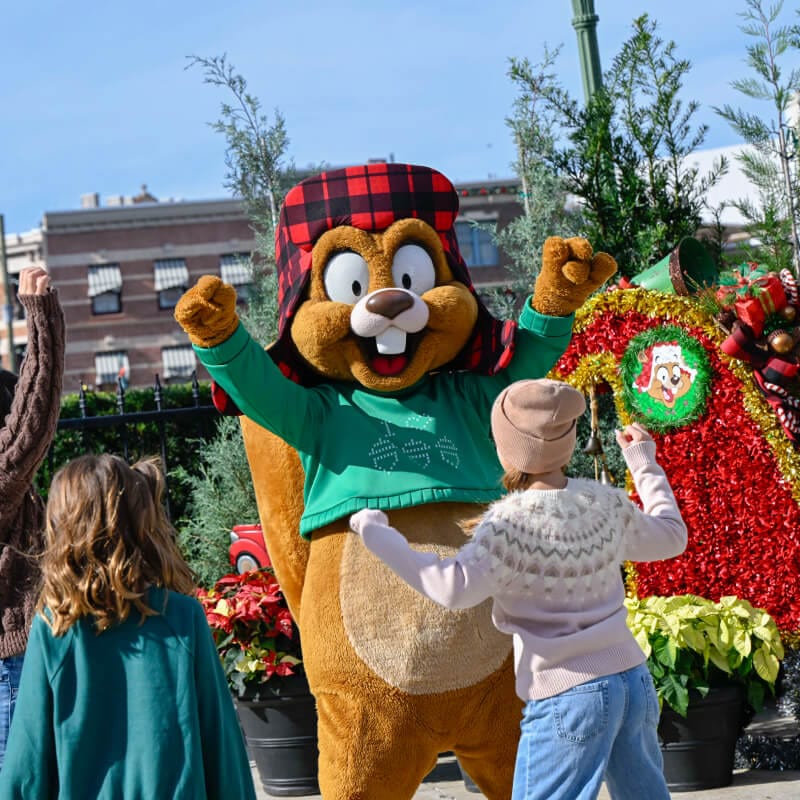 Kids dance and cheer on Earl the Squirrel alongside a festive tree at Universal Studios Florida.
