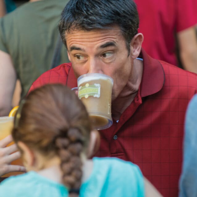 Dad and the kids sipping frothy Butterbeer at The Hopping Pot in The Wizarding World of Harry Potter Diagon Alley in Universal Studios Orlando.