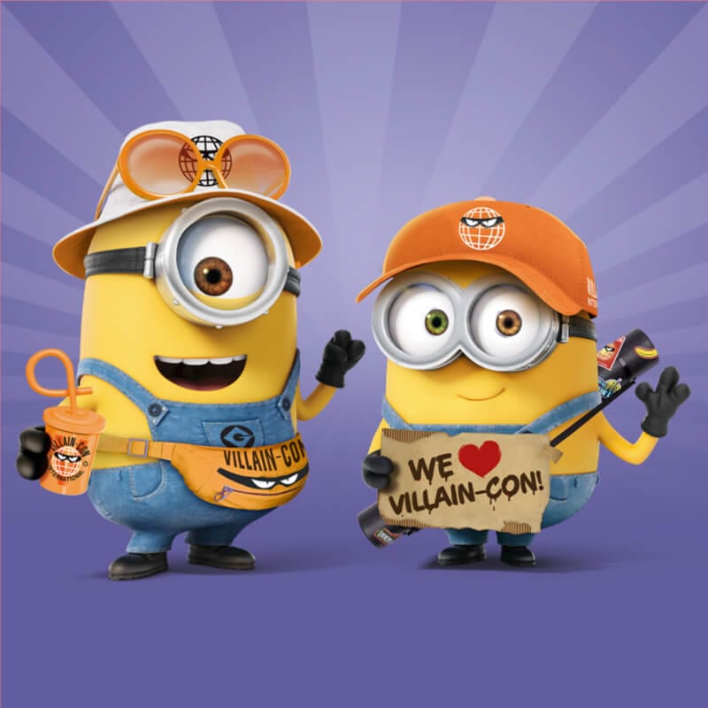 Two minions waving dressed in Villain Con merch