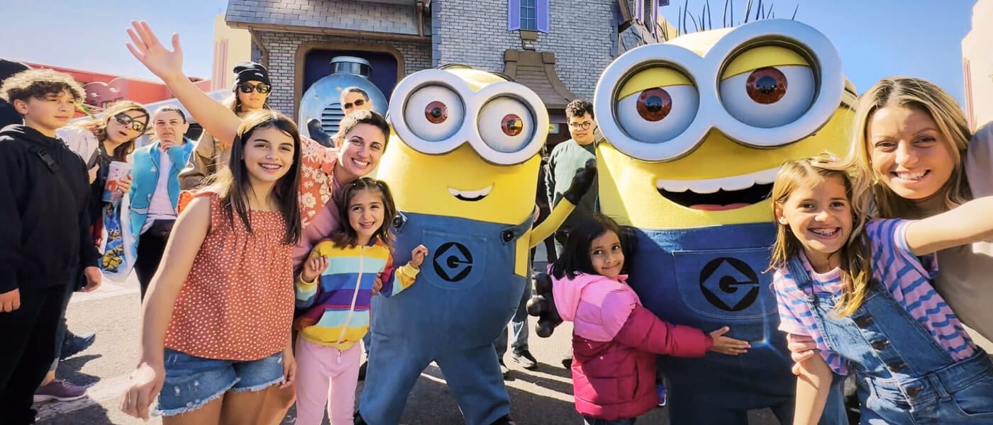 Two minions pose with a group of park guests in front of Despicable Me Minion Mayhem at Universal Studios Florida.