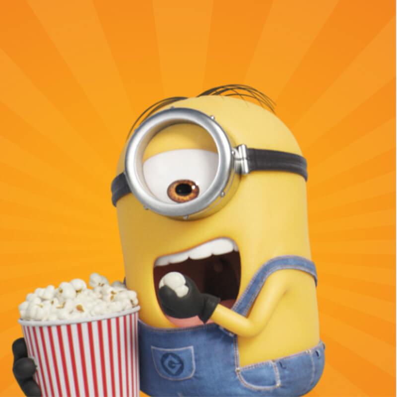 A minion eating popcorn while holding a popcorn bucket