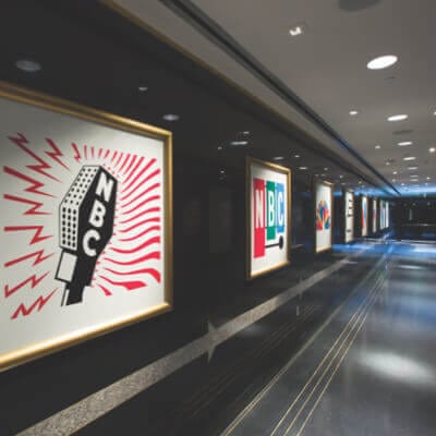 Race Through New York Starring Jimmy Fallon Fast Fact 1 vintage NBC Radio and Broadcasting logos hanging in picture frames along the 30 Rock hallway