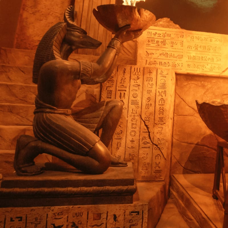 A statue of an ancient Egyptian god alongside a wall of hieroglyphics in the Revenge of the Mummy ride.