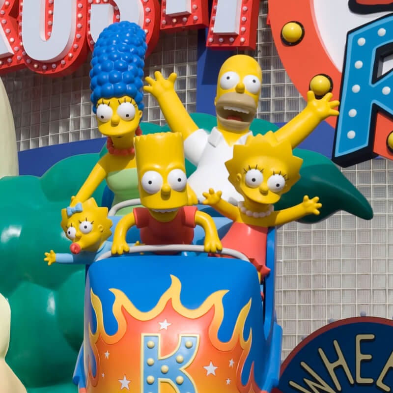 A colorful statue of the Simpsons family riding a roller coaster car in front of The Simpsons Ride at Universal Studios in Orlando.