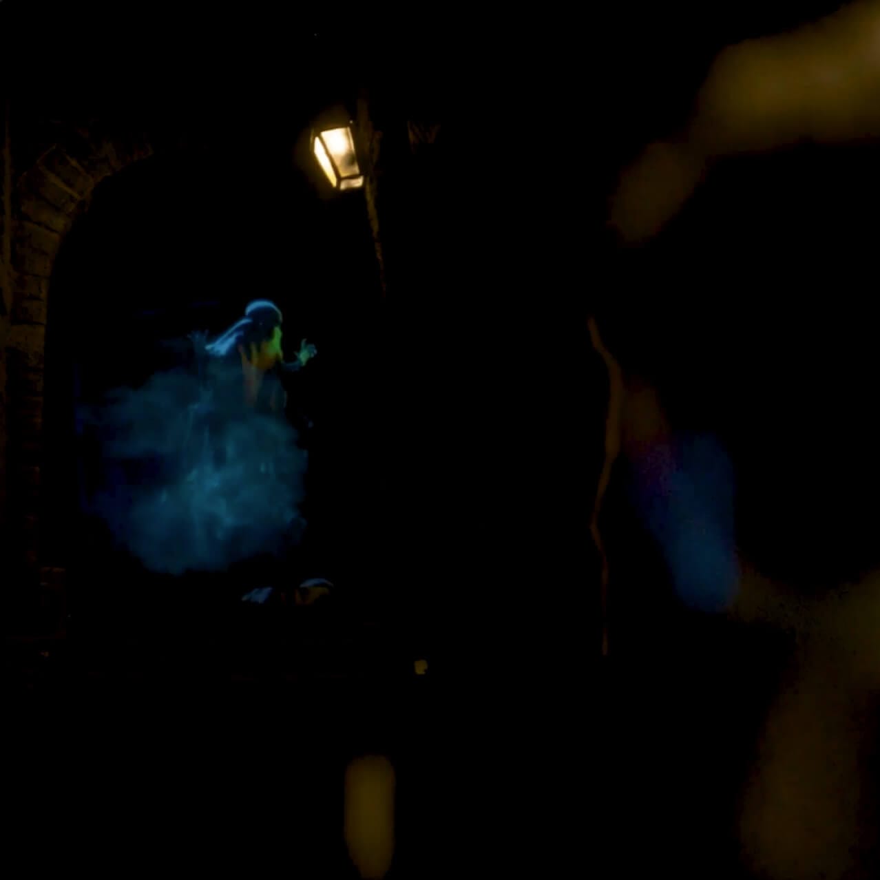 A guest in wizard robes gazes at a glowing Dementor hovering above a dark Knockturn Alley staircase.