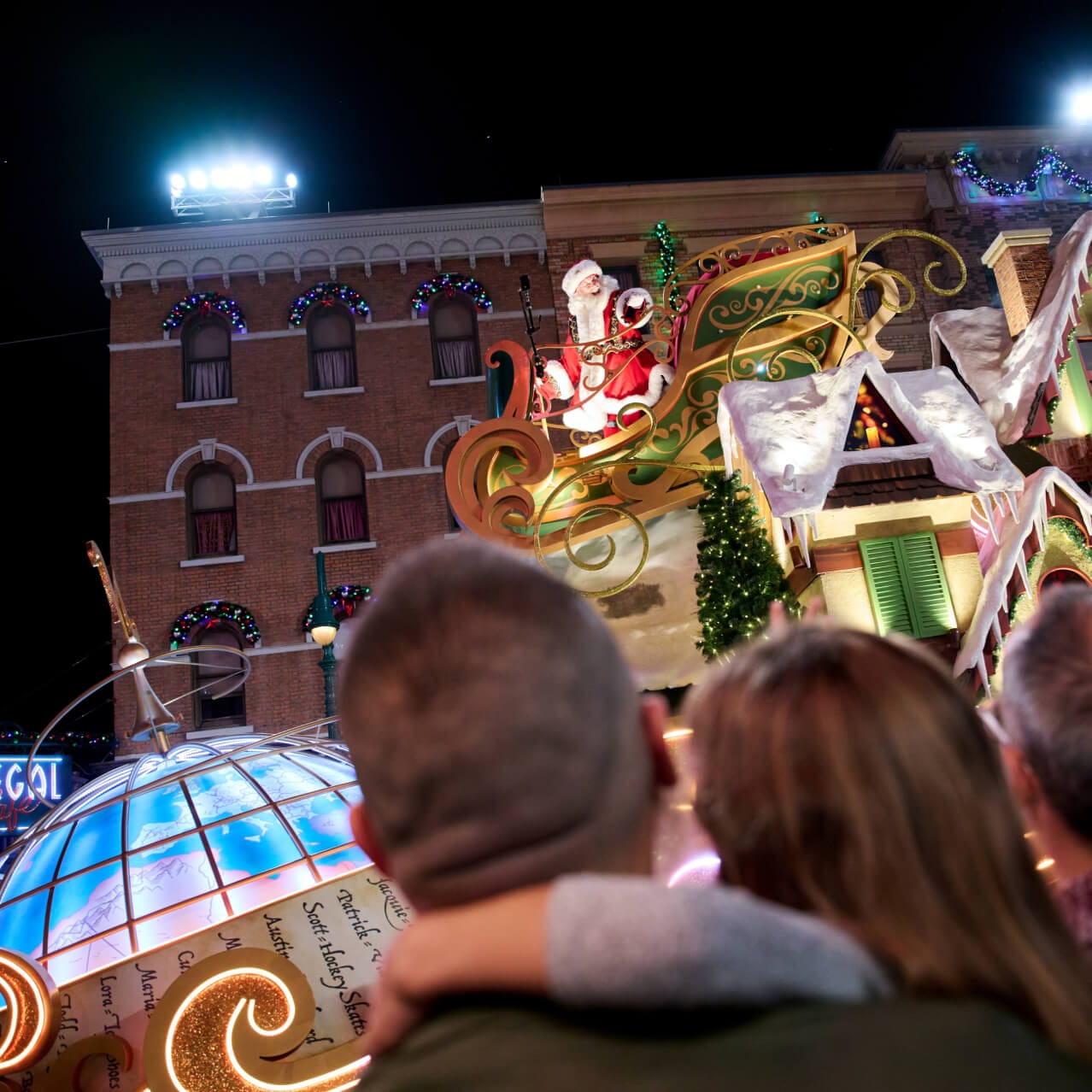 People watching a parade float of Santa in his sleigh on a housetop going by during Holidays at Universal Orlando.