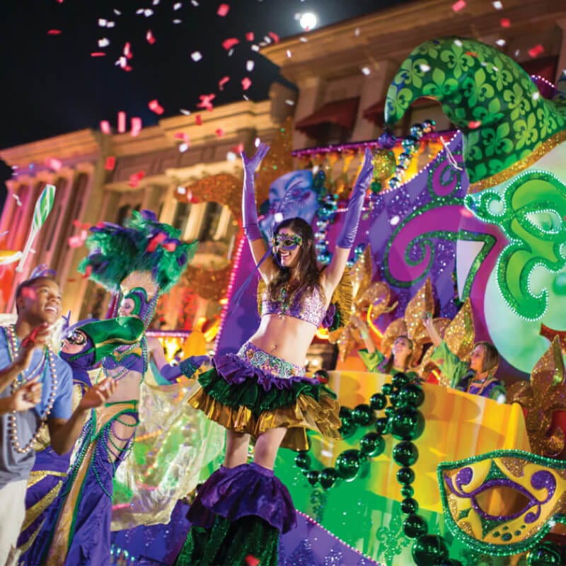 A stilt walker waves her arms in cheer as the audience watches the Mardi Gras parade go past.