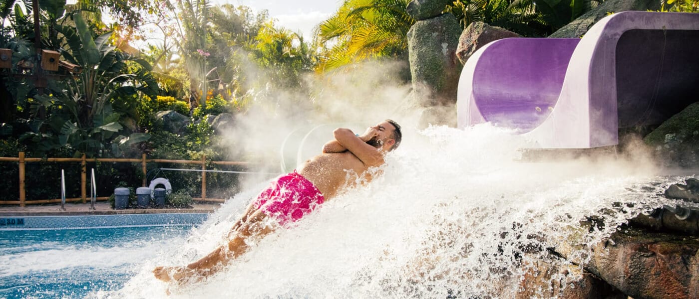 Man with his arms crossed flies off the end of the Ohno Drop Slide into a pool at Universal Volcano Bay.