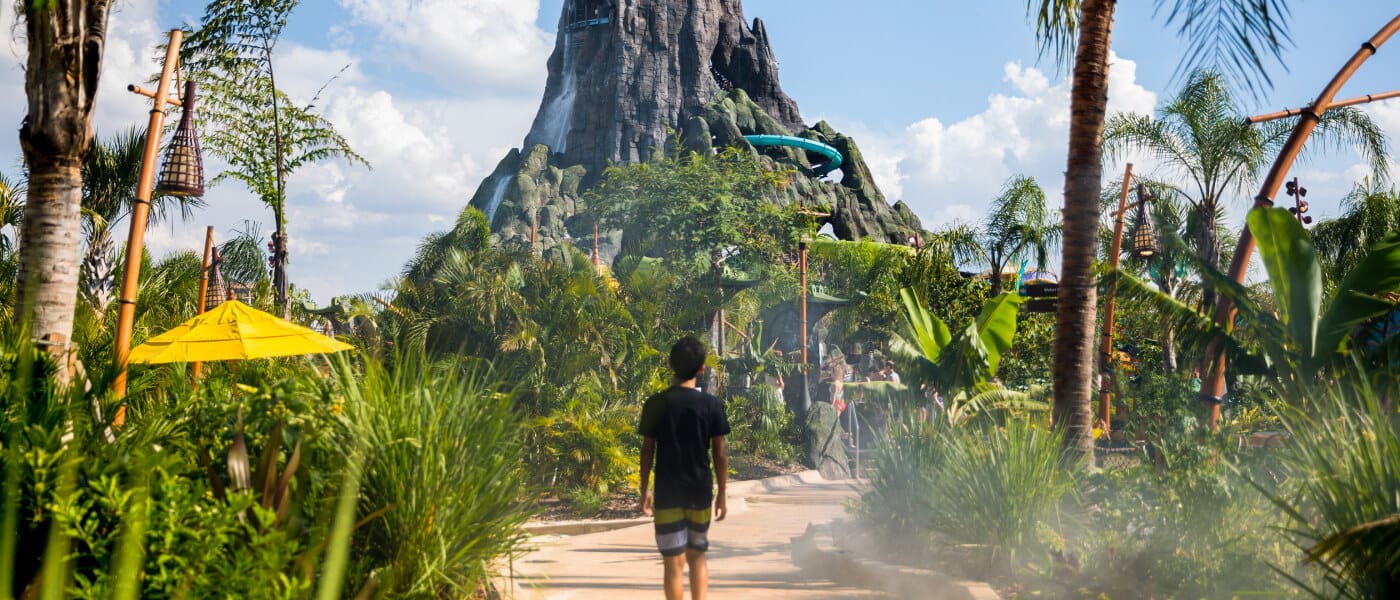 A boy walks down a path leading toward the Krakatau Volcano at Universal Volcano Bay.