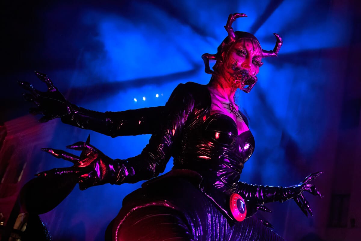 A scorpio-themed scareactor surrounded by a foggy blue halo, poses with arms raised.