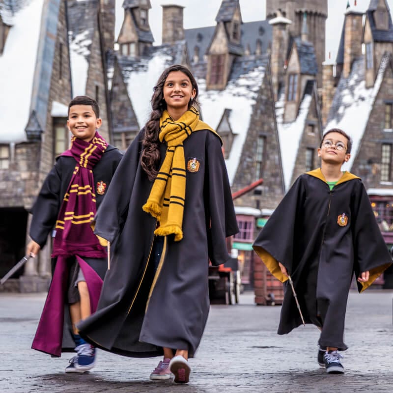Wearing&nbsp;wizard&nbsp;robes&nbsp;and&nbsp;carrying&nbsp;wands,&nbsp;three&nbsp;children&nbsp;walk&nbsp;together&nbsp;through&nbsp;Hogsmeade&nbsp;village&nbsp;at&nbsp;Universal’s&nbsp;Islands&nbsp;of&nbsp;Adventure.