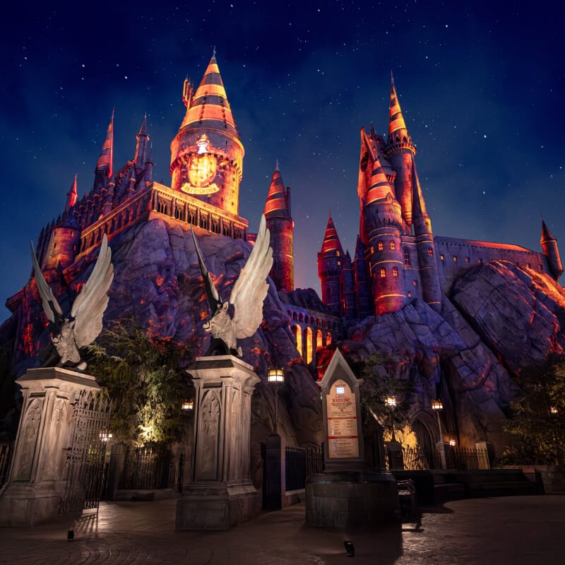 A nighttime projection show “Hogwarts Always” lighting up Hogwarts castle in purple and orange hues against a starry sky.