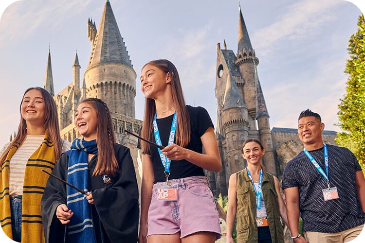 A group of Passholders carry wands in front of Hogwarts™ castle at Universal Islands of Adventure