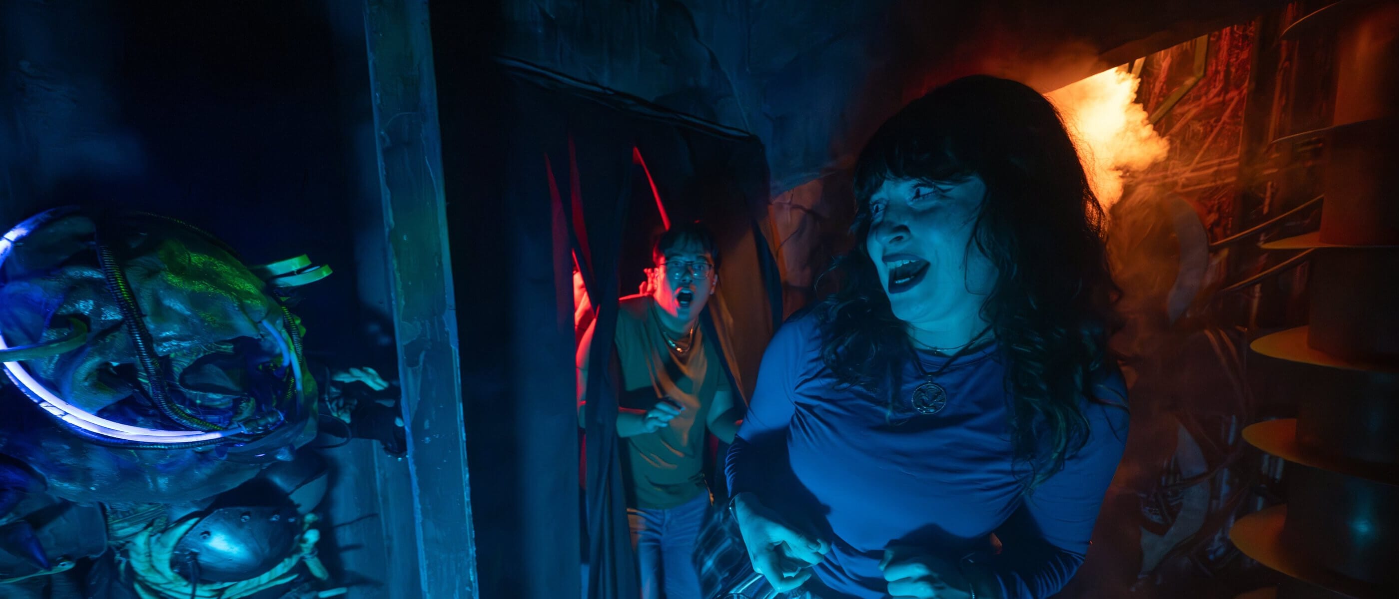 Two startled guests encountering a slimy creature with cybernetic enhancements hiding around the next corner.