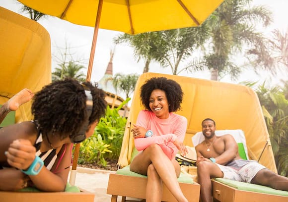 At Volcano Bay, a family unwinds together sitting on a set of private loungers on the beach.