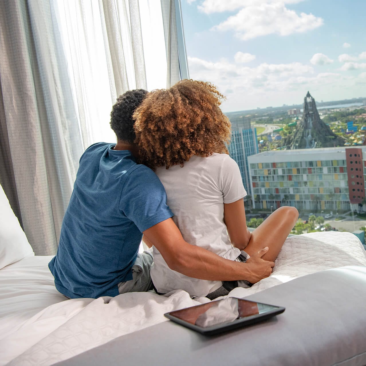 Una pareja mira hacia Volcano Bay desde la ventana de su hotel de Universal Orlando.