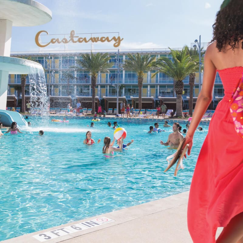 Una mujer camina frente a una piscina grande en Universal Cabana Bay Beach Resort.