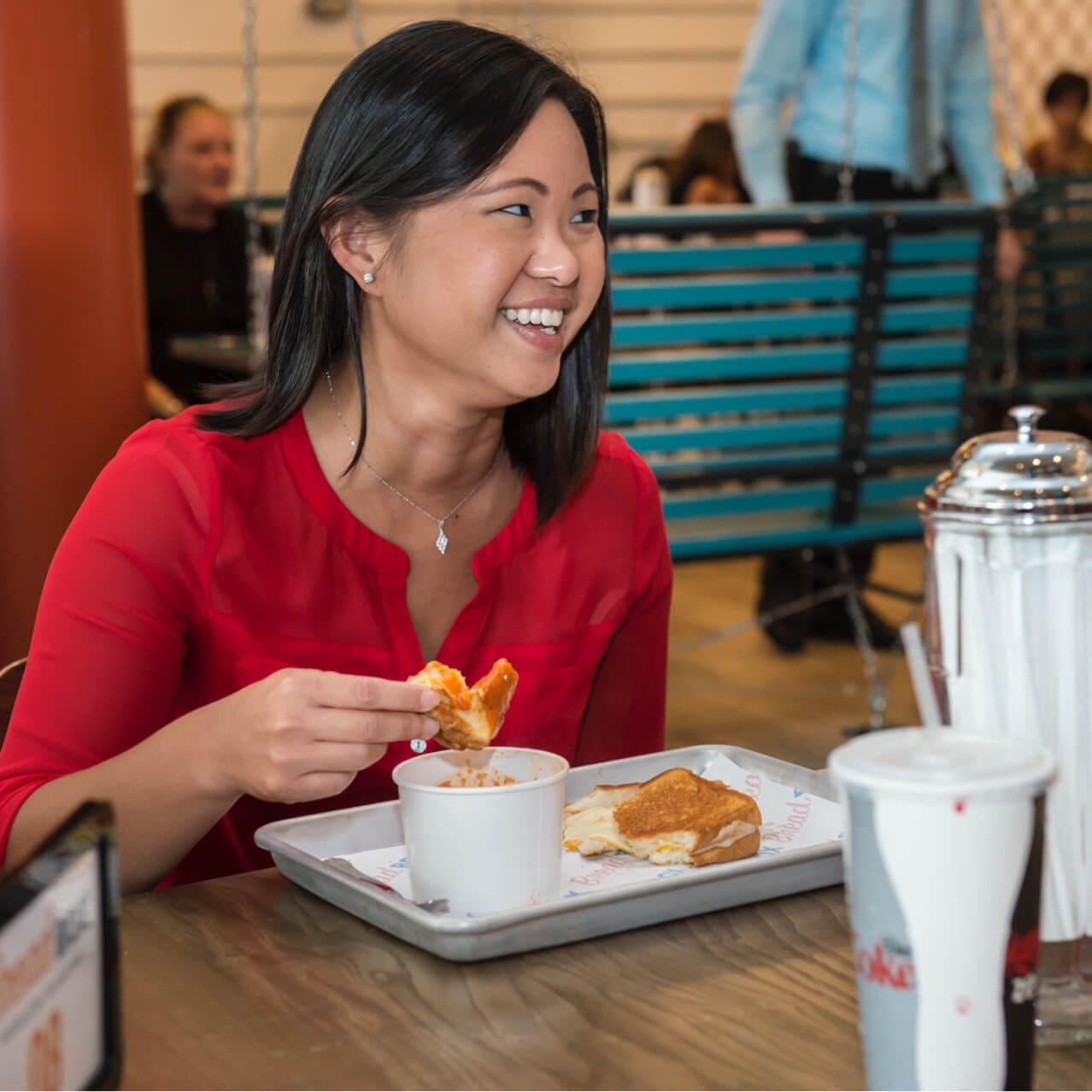 A woman smiles as she eats inside Bread Box Handcrafted Sandwiches at Universal CityWalk. 