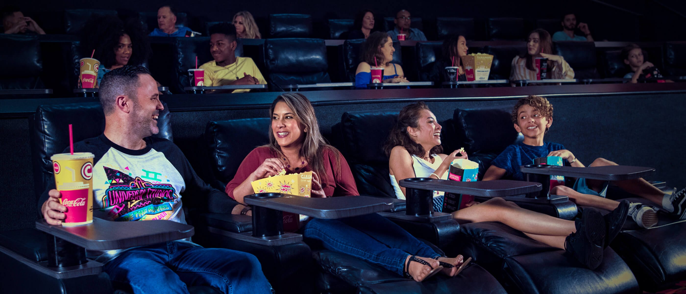Una familia en asientos reclinables conversando y disfrutando de unos bocadillos antes de ver una película en Universal Cinemark de Universal CityWalk Orlando.