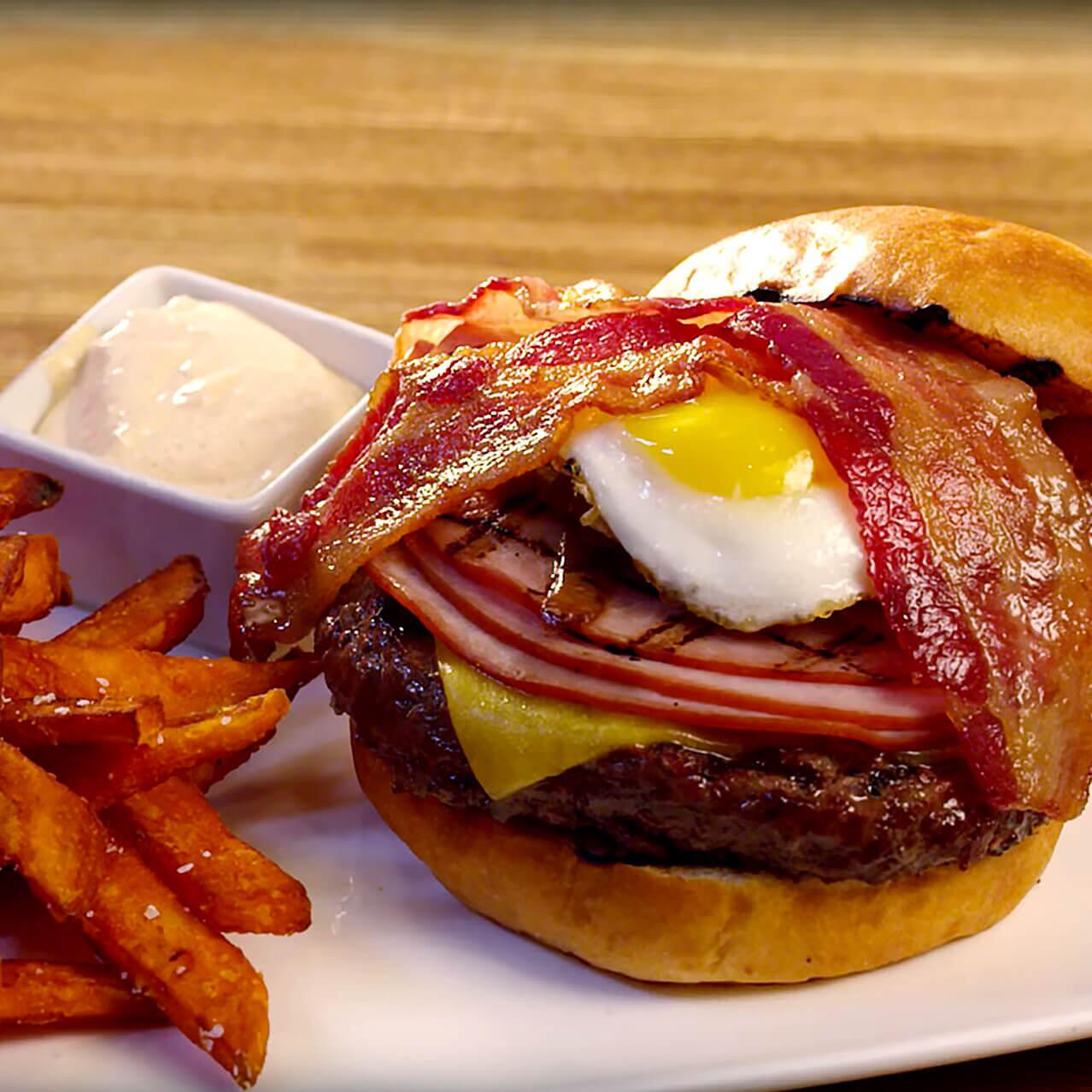 Una imagen de un hamburger decorado con un huevo frito y tocino de un video sobre Cowfish Sushi Burger Bar, un restaurante de fusión innovadora en Universal CityWalk Orlando.