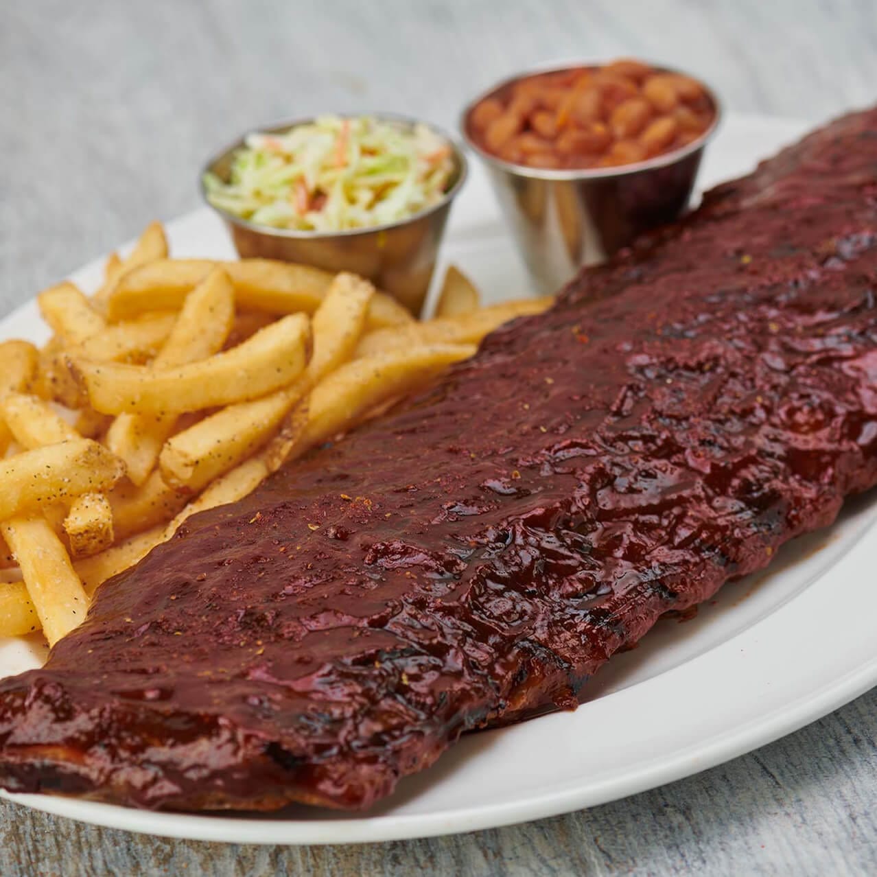 Costillitas de cerdo servidas con papas fritas, ensalada de col y frijoles horneados de Hard Rock Cafe Orlando.