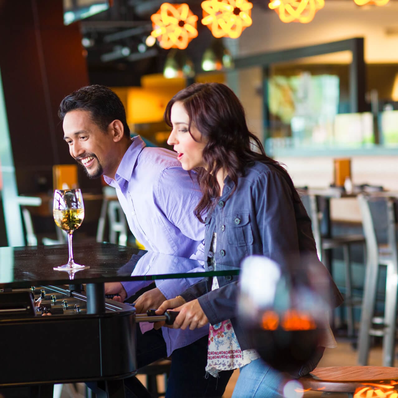 Un hombre y una mujer juegan foosball en una mesa divertida dentro del NBC Sports Grill And Brew, un restaurante ideal para toda la familia en Universal CityWalk Orlando.